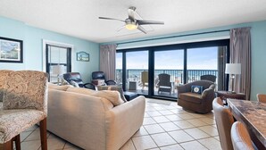 A spacious living room with a large sofa, a dining table, and a ceiling fan. - Ocean Breeze East 201 (Pensacola)