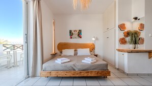 A bedroom with a wooden bed, a painting on the wall, and a view of the outside balcony. - Kalimera studio 3 ,Near beach and all amenities (Adelianos Kampos)