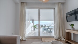 A modern living room with a sofa, a coffee table, and a TV mounted on the wall. - Mythos villa 8,pool,Walking distance to beach (Damnoni)