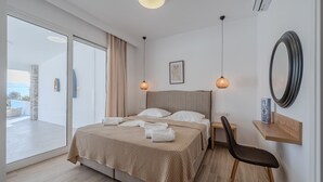 A modern bedroom with a large bed, a desk, and a chair. There is a large window with a view of the outdoors. - Mythos villa 8,pool,Walking distance to beach (Damnoni)