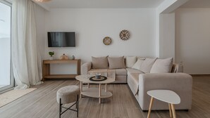 Ein modernes Wohnzimmer mit einer Couch, einem Couchtisch, einem Fernseher und einem Holztisch.