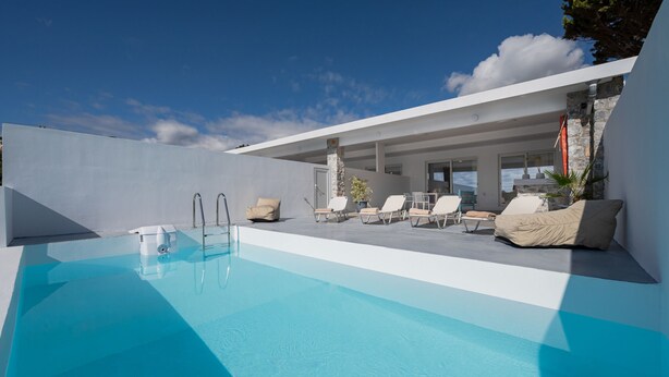 Ein moderner Poolbereich im Freien mit Liegestühlen und blauem Himmel.