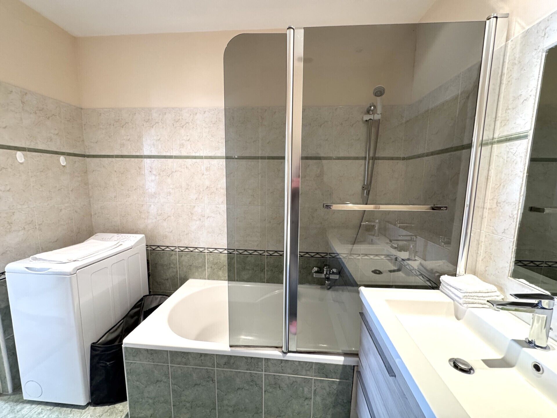 Een badkamer met een douchecabine, een wit bad en een wasmachine.