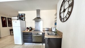 A compact kitchen with a stove, oven, sink, and a clock on the wall.