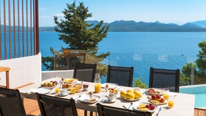 A dining table with breakfast items and a view of a lake and mountains. - Villa Selina in Nikiana (Lefkada)