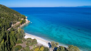 An aerial view of a coastal area with a beach, clear blue waters, and dense green forest. - Villa Selina in Nikiana (Lefkada)
