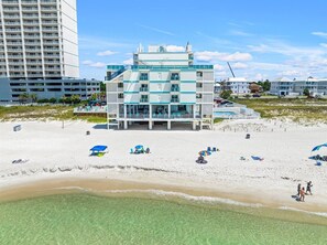 A beachfront hotel with multiple floors, a pool, and beach umbrellas. - Beachfront Studio | Amazing Sunsets | Pool (Panama City Beach)