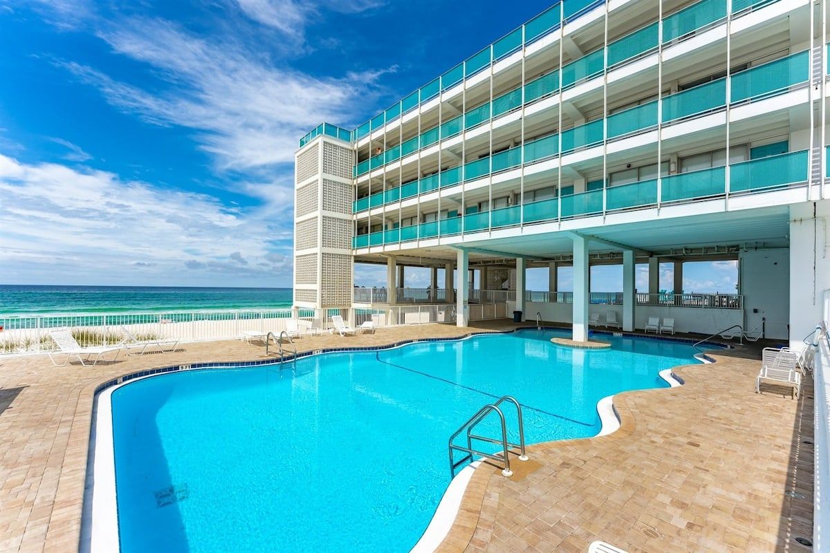 A multi-story building with a swimming pool and a view of the ocean.