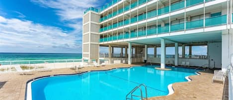 A multi-story building with a swimming pool and a view of the ocean.