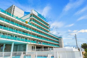 Un hôtel à plusieurs étages, doté d’une enseigne bien visible, de balcons et d’un espace piscine.