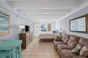 A spacious room with a bed, a sofa, a desk, and a television.