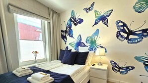 A hotel room with a bed, a nightstand, a lamp, and a window with curtains.