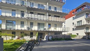 A multi-story residential building with balconies, a paved courtyard, and a bike rack.