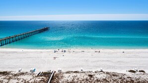 A beach with a pier extending into the ocean, sandy beach, and clear blue water. - Summerwind Center 1204 (Navarre)