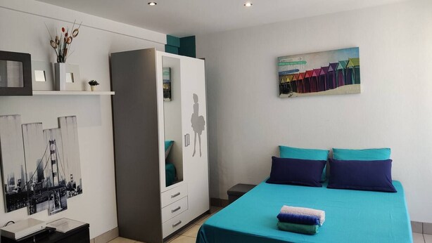 A bedroom with a bed, a wardrobe, a desk, and a painting on the wall. - Air-conditioned studio 2 min from the beach - Centre Juan-les-Pins (Antibes)