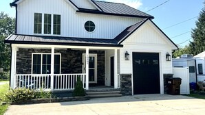 Et toetagers hus med en veranda, garage og en facade af sten.