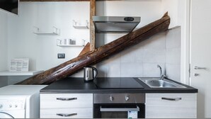 A kitchen with a large wooden beam, a kettle, a sink, and a stove. - Italianway - Rosmini 11 B (Milan)