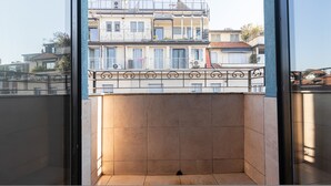 A balcony with a tiled floor, a metal railing, and a view of buildings in the background. - Italianway - Rosmini 11 B (Milan)