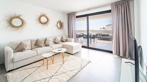 A modern living room with a sofa, two side tables, and a large sliding glass door leading to an outdoor patio area.