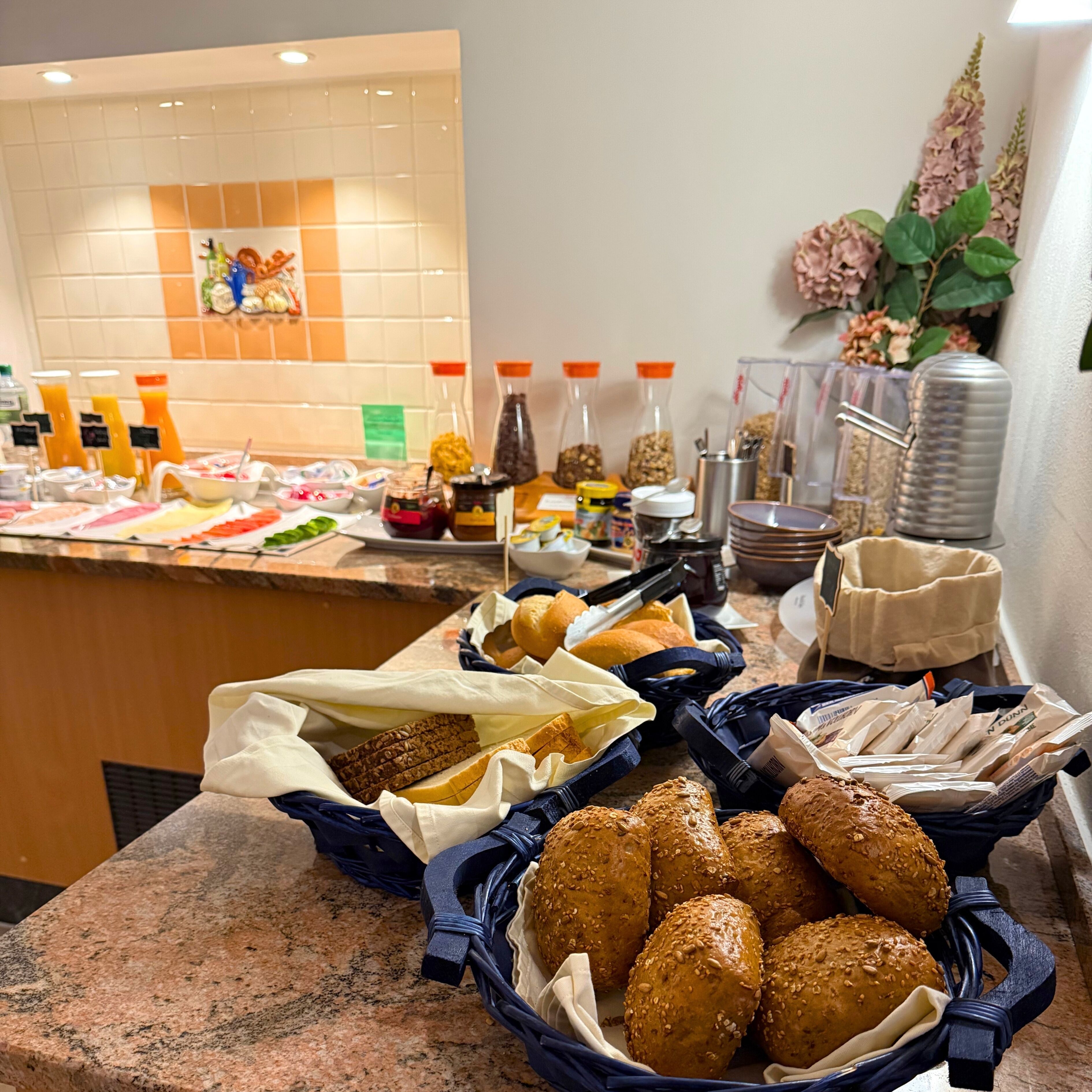 Ein Buffet mit verschiedenen Speisen, darunter Brot, Gebäck und Beilagen.