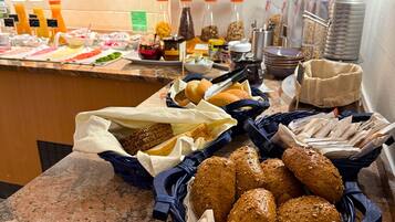 Ein Buffet mit verschiedenen Speisen, darunter Brot, Gebäck und Beilagen.
