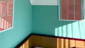 A room with teal walls, a wooden headboard, and two framed posters with text. - Colourful Hotel (Bielefeld)
