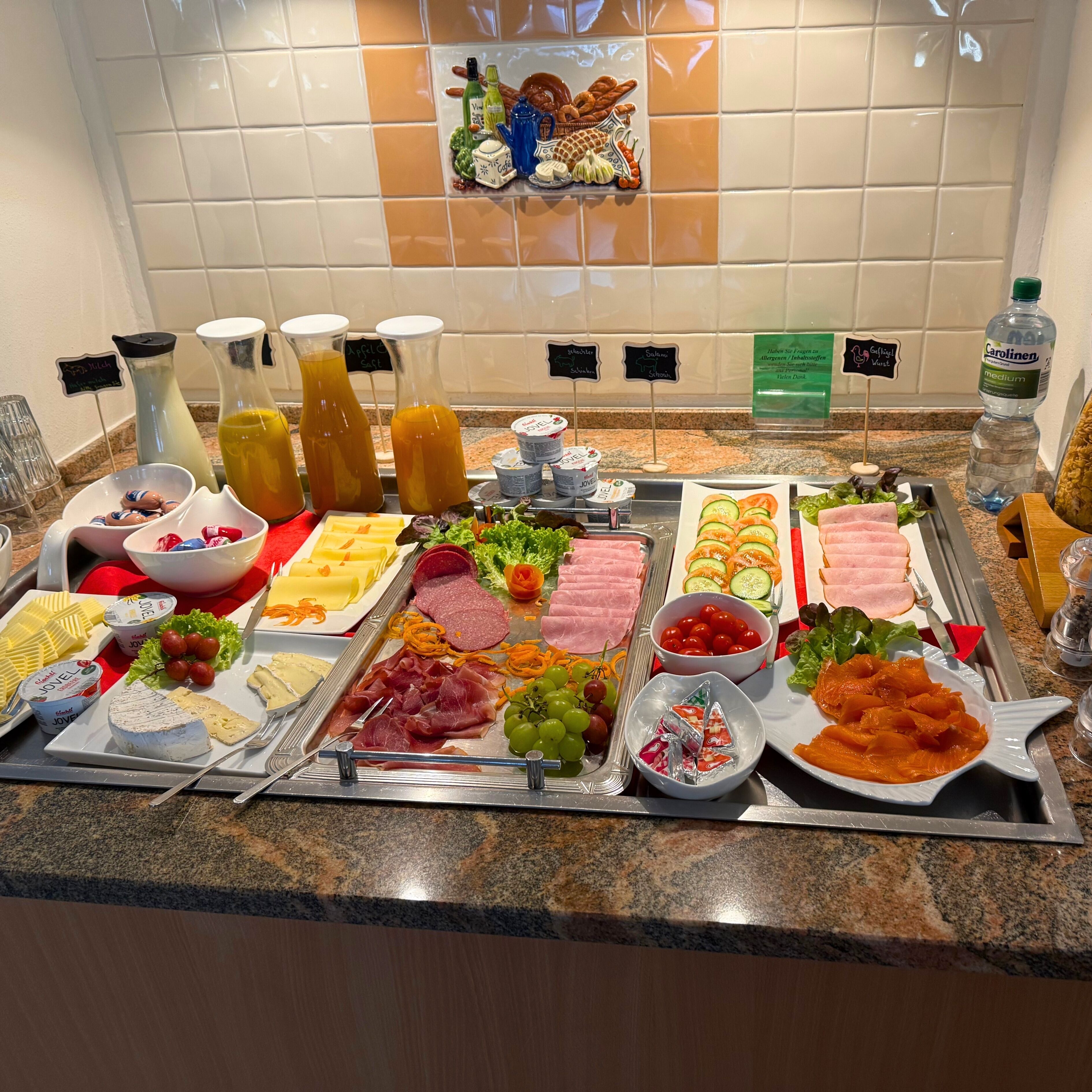 Un bufé con una variedad de alimentos, incluyendo carnes, quesos, frutas y salsas.
