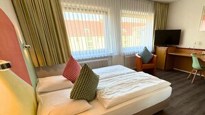 A hotel room with a bed, a desk, a chair, and a television. - Colourful Hotel (Bielefeld)