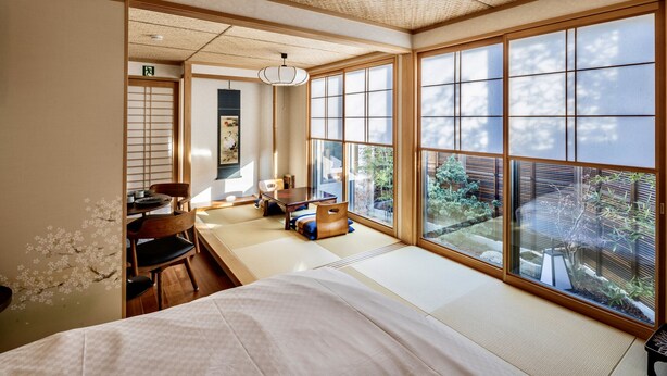 A traditional Japanese room with tatami flooring, a low table, and a bed. - Kamogawa House- Exquisite two-story home with a japanese garden (Kyoto)