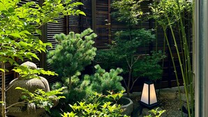 A traditional Japanese garden with bamboo, pine trees, and a stone lantern. - Kamogawa House- Exquisite two-story home with a japanese garden (Kyoto)