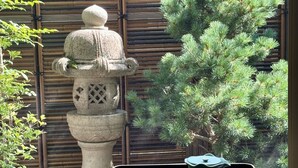 A traditional Japanese room with tatami flooring, a shoji screen, a stone lantern, and a bonsai tree. - Kamogawa House- Exquisite two-story home with a japanese garden (Kyoto)
