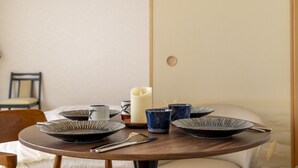 A neatly arranged dining table with plates, cups, and a candle. - Kamogawa House- Exquisite two-story home with a japanese garden (Kyoto)
