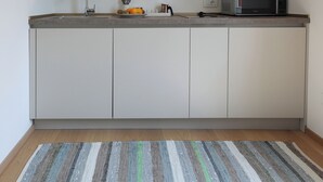 A modern kitchen with white cabinets, a microwave, and a wooden ceiling. - Nine Rooms Apartment (Trento)