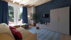 A modern living room with a sofa, a television, a wardrobe, and a potted plant. - Nine Rooms Apartment (Trento)