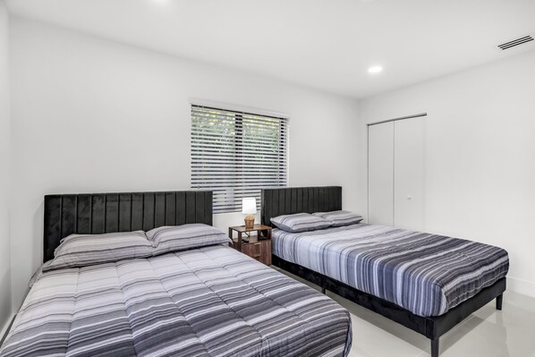 A bedroom with two beds, a window with blinds, a bedside table with a lamp, and a wardrobe. - 5 BDR, 9 beds, Sleeps 12, Luxury Oasis Pool, 6 miles to beach (Miami)