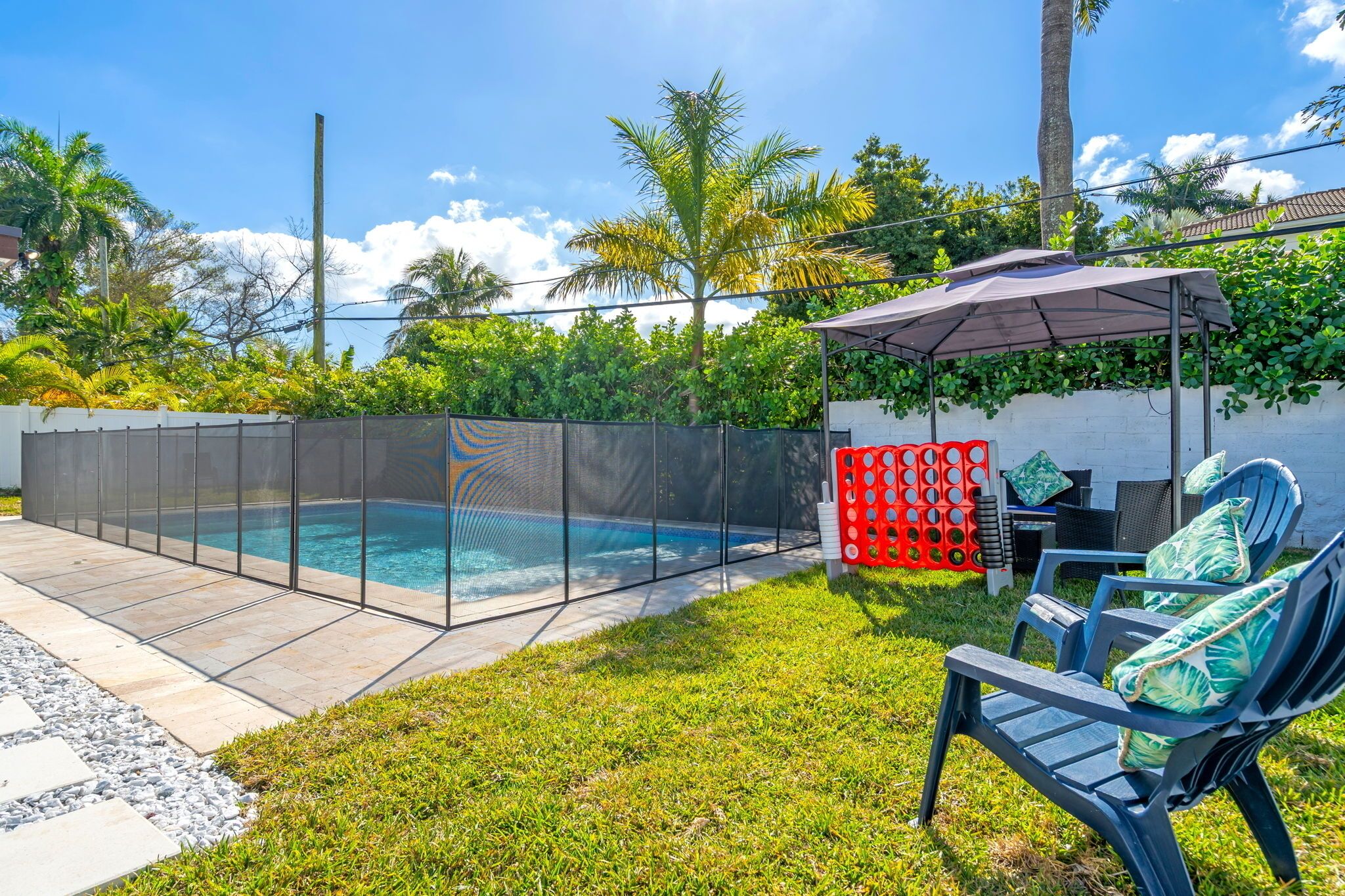A backyard with a swimming pool, a covered seating area, and a red play structure.