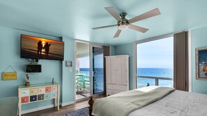 A bedroom with a bed, a ceiling fan, a TV on the wall, a dresser, and a view of the ocean. - Shoreline Towers 1073 (Destin)