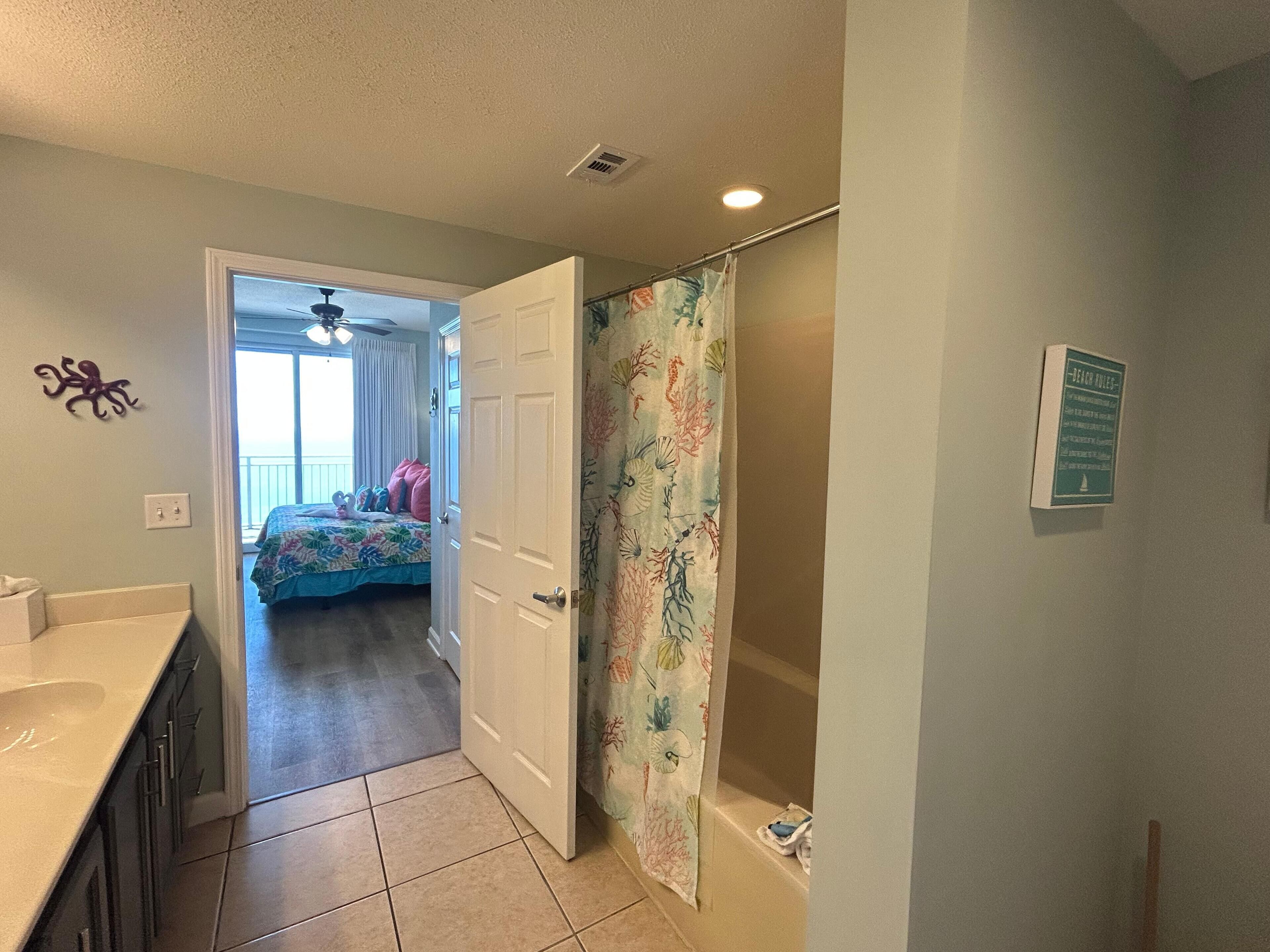 A bathroom with a shower curtain, a toilet, and a sink.