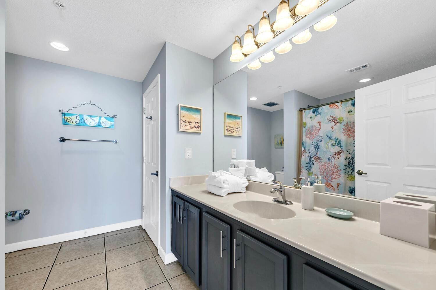 A modern bathroom with a large mirror, a sink with a vanity, and a shower with a colorful curtain.