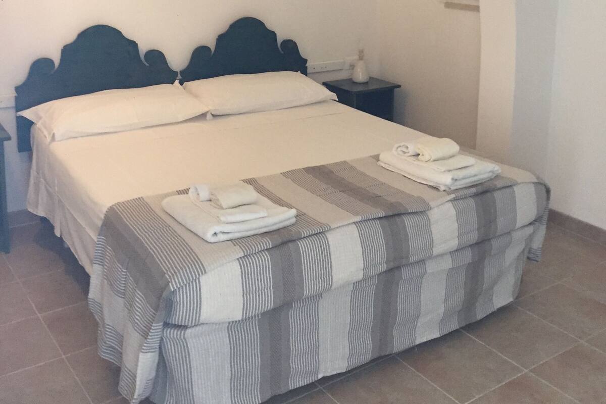 Ein Bett mit Kopfteil, ein Nachttisch und eine Wandlampe.