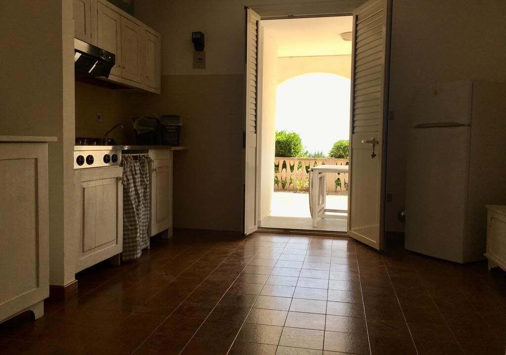 Una cocina con estufa, armarios y vistas a un patio exterior.