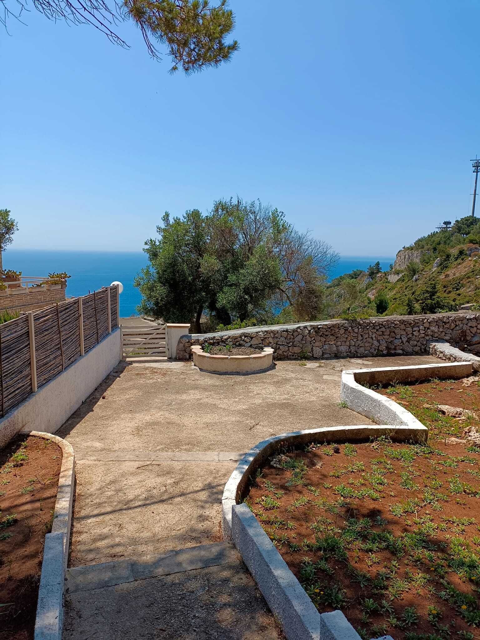 A paved pathway leading to a scenic overlook with a view of the sea.