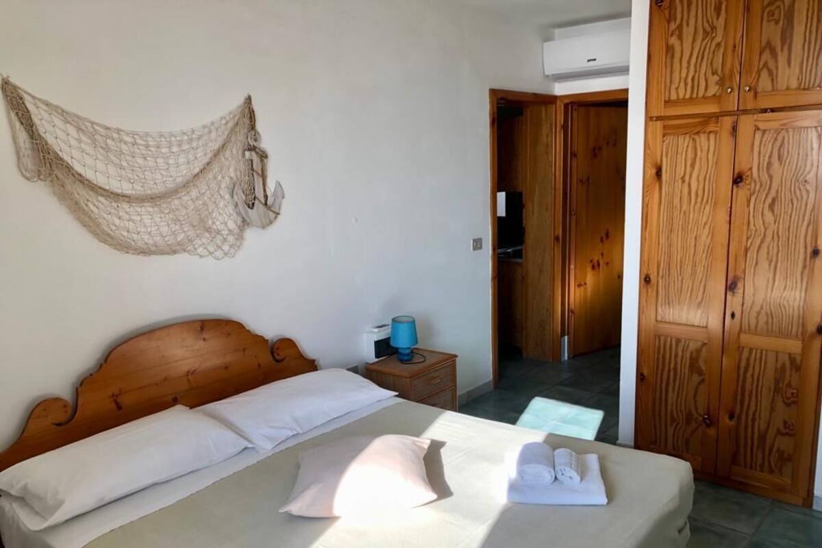 Ein Schlafzimmer mit einem hölzernen Bett, einem Nachttisch mit Lampe, einem Hängevorhang und einem Kleiderschrank.
