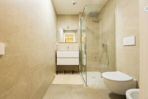 A modern bathroom with a glass shower enclosure, a white toilet, and a vanity with a mirror. - Genoa East Waterfront DeLuxe Flat (Genoa)