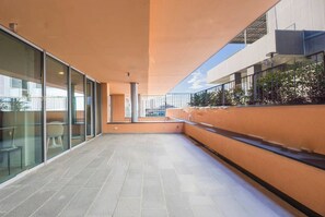 A modern building with a covered walkway, glass walls, and outdoor seating. - Genoa East Waterfront DeLuxe Flat (Genoa)