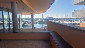 Un edificio moderno con balcón que da a un puerto deportivo con barcos.