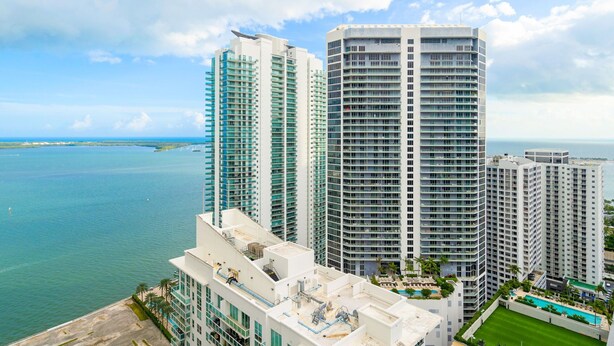 A high-rise hotel with multiple floors, a rooftop pool, and a view of the ocean.