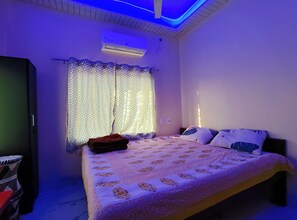 Relax in this serene bedroom with a comfortable bed, a spacious wardrobe, and a window with patterned curtains.