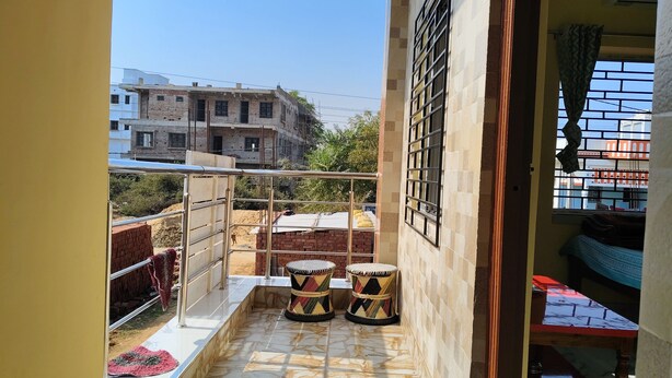 Ein Balkon mit Fliesenboden, einem Metallgeländer und zwei Zierhockern.
