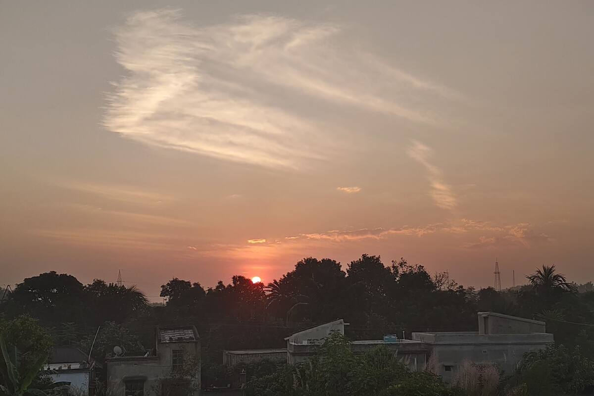 Un coucher de soleil sur une zone résidentielle, avec des maisons et des arbres.